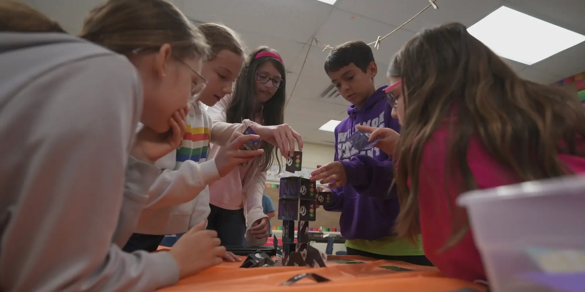 Five students working together on a card tower QUEST challenge