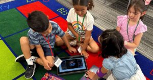 Four primary students sitting together on the carpet following the Starforce story on a tablet