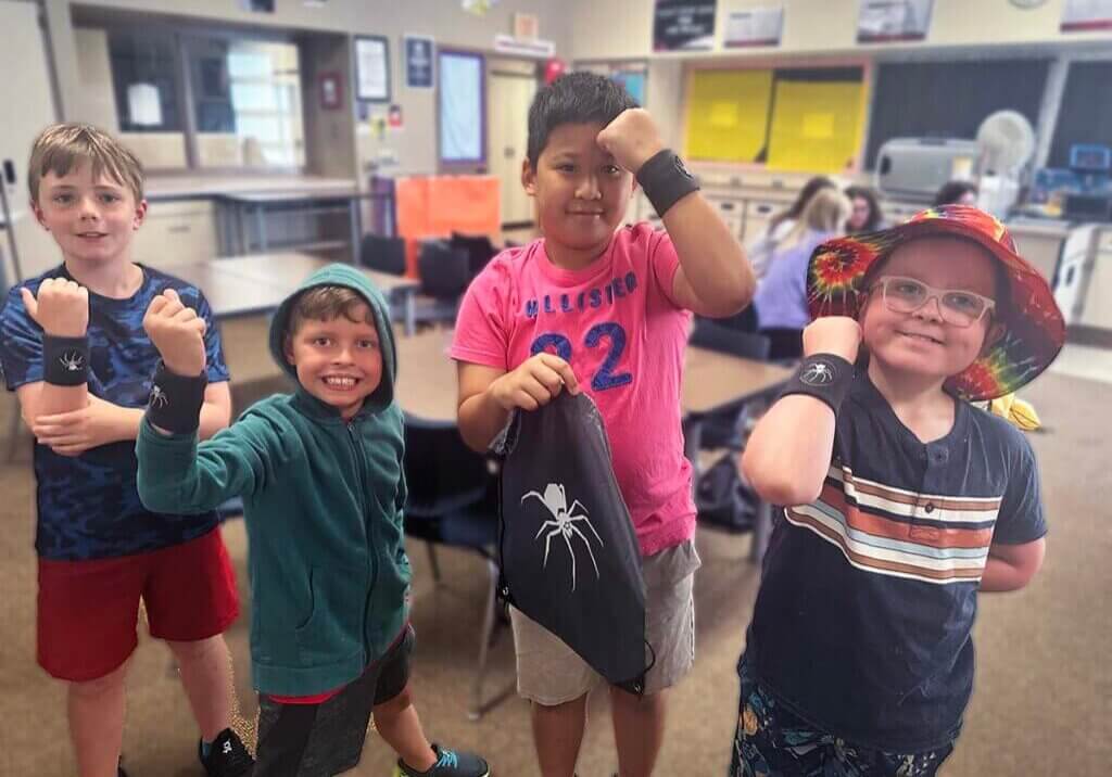 QUEST students on the black spider team showing off their team wristbands